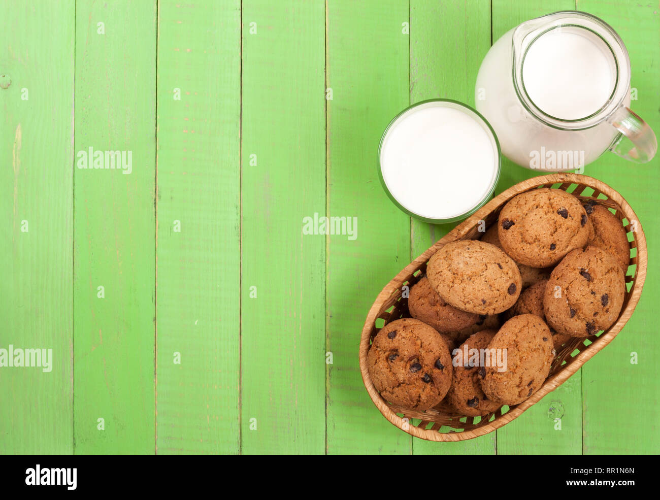 Brocca e bicchiere di latte con farina di avena i cookie su un verde sullo sfondo di legno con una copia dello spazio per il tuo testo. Vista superiore Foto Stock