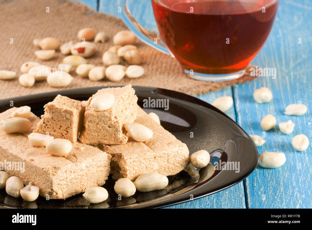 Peanut halva nella piastra su un blu sullo sfondo di legno Foto Stock