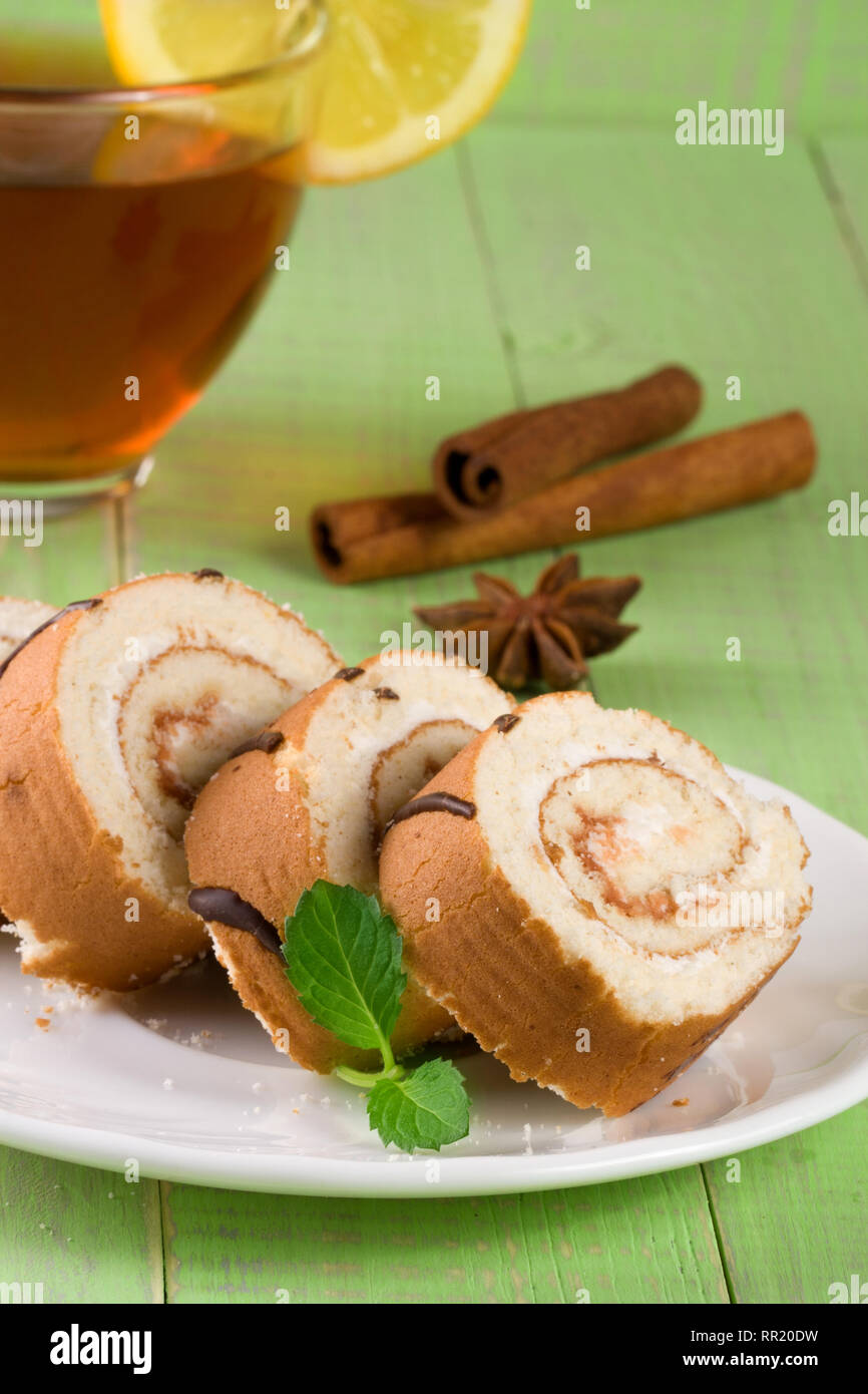 Biscuit rotolo svizzero con una tazza di tè verde su sfondo di legno Foto Stock