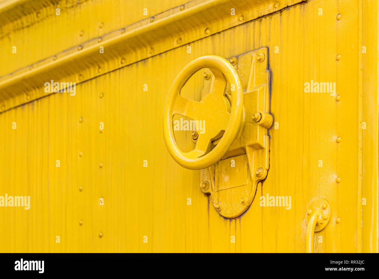 Valvola industriale ruota su sporco metallo giallo sullo sfondo della piastra Foto Stock