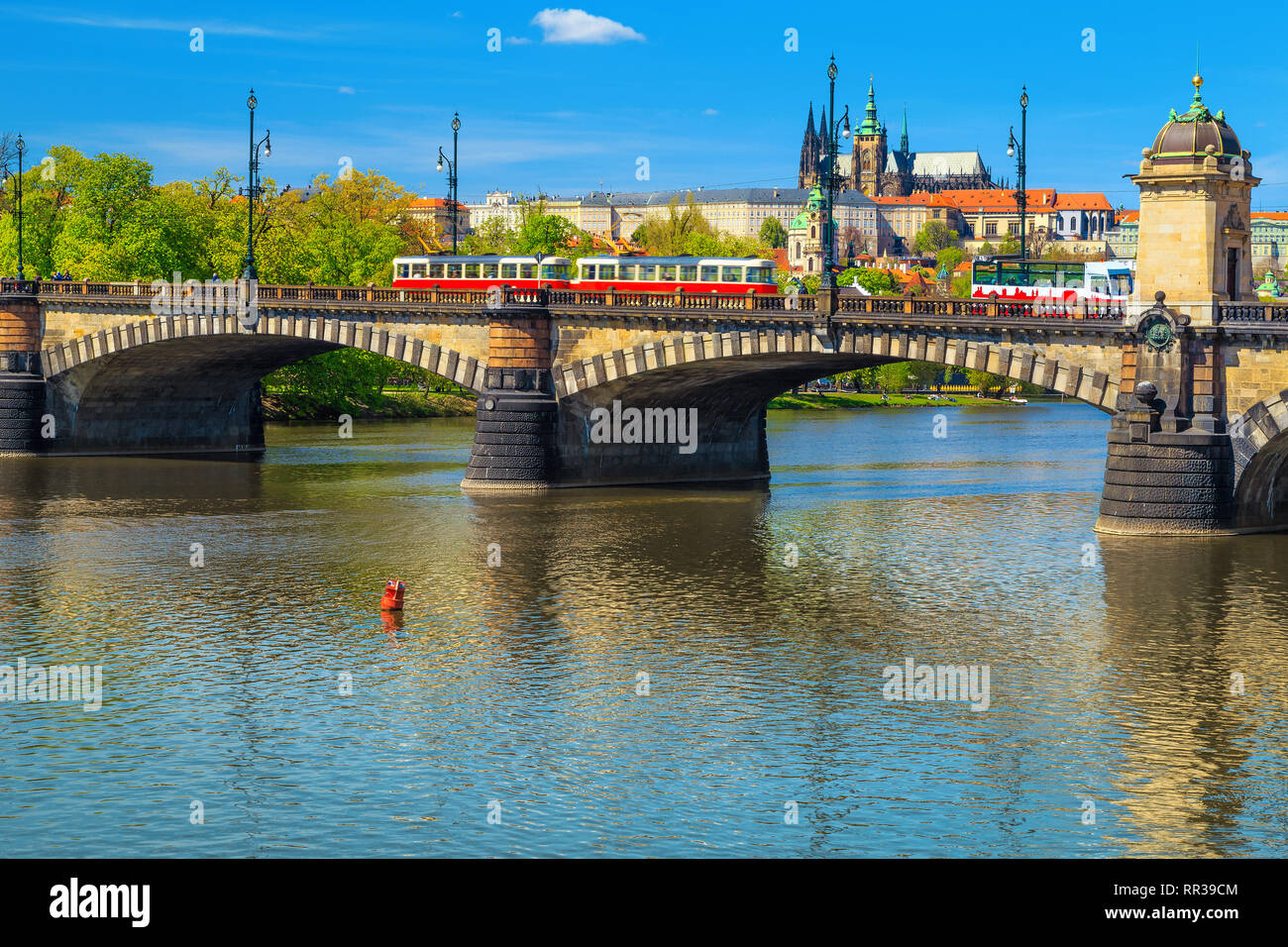 Europea di destinazione di viaggio, un antico ponte in pietra sul fiume Vltava con red tram turistico e bus del passeggero. Estate paesaggio urbano di Praga con build storici Foto Stock