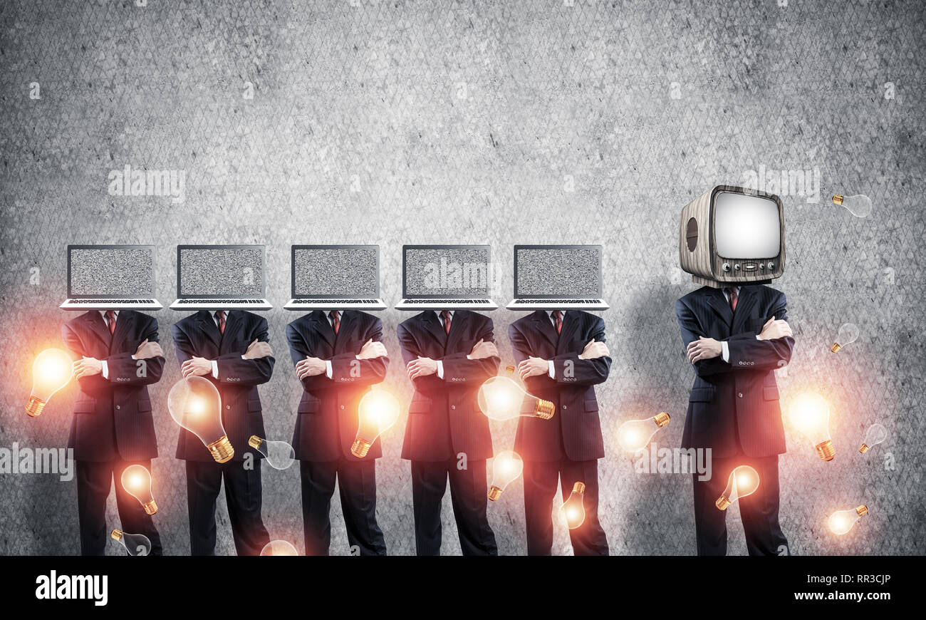 Uomini d'affari in giacca con i laptop invece dei loro capi mantenendo le braccia incrociate mentre sta in piedi in una riga e uno in testa con il vecchio TV in stanza vuota ag Foto Stock