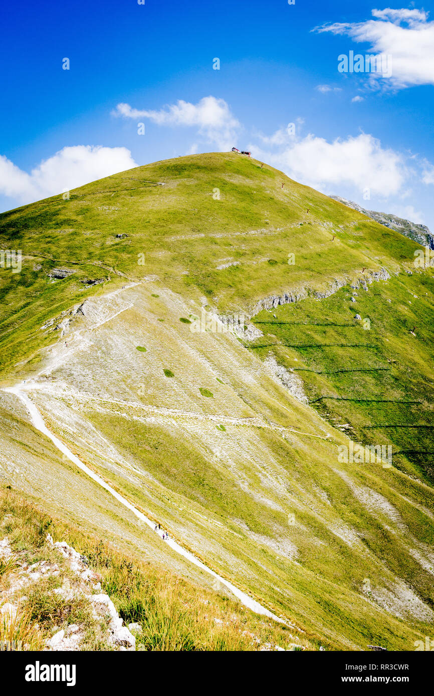 Ripresa a tutto campo della montagna verde con persone sul sentiero che sale al yop, soleggiata giornata estiva Foto Stock