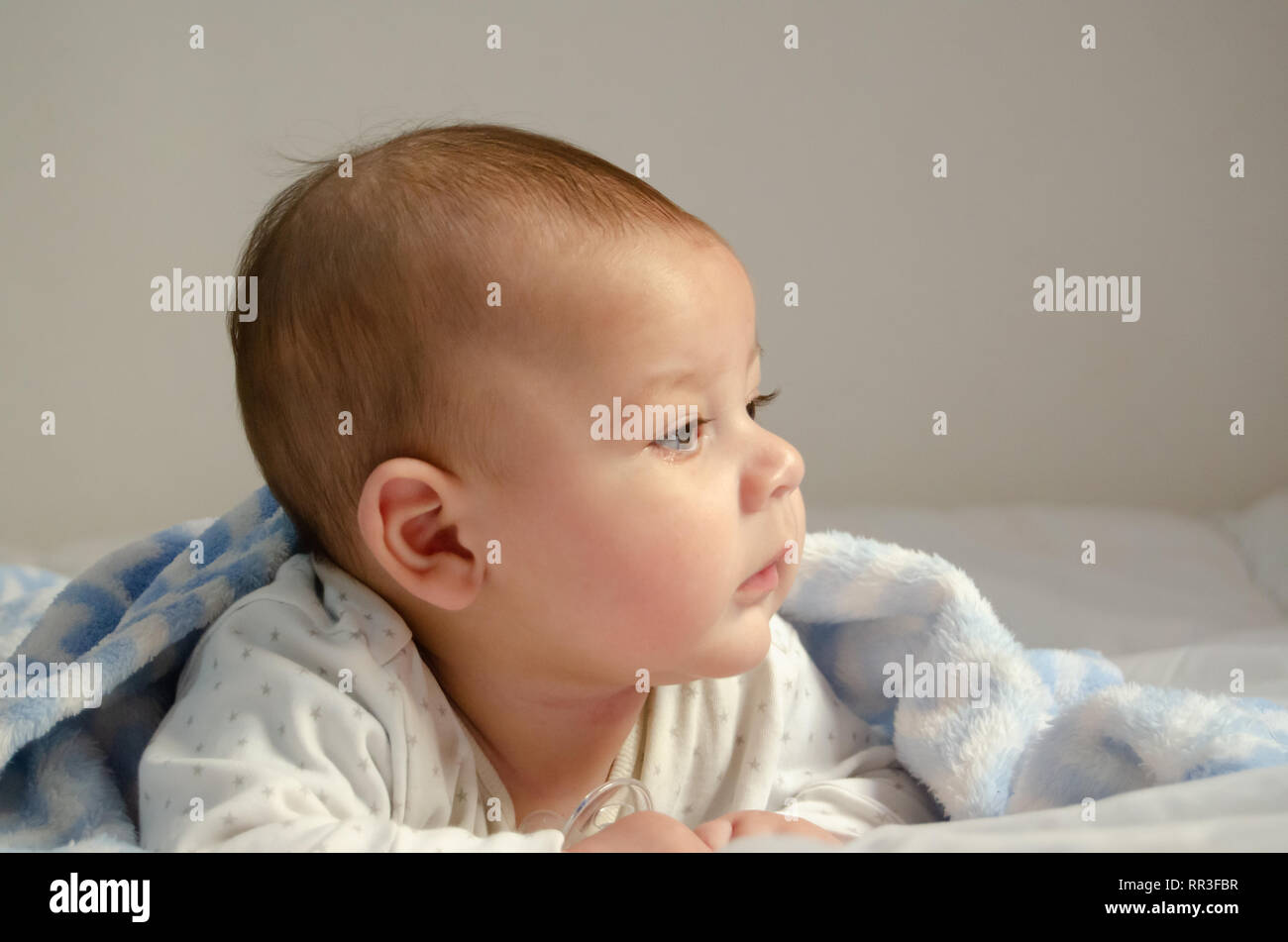 Carino 4 mesi baby boy avente pancia tempo sul panno bianco coperto con blue blanket - Salute e infanzia felice concetto Foto Stock