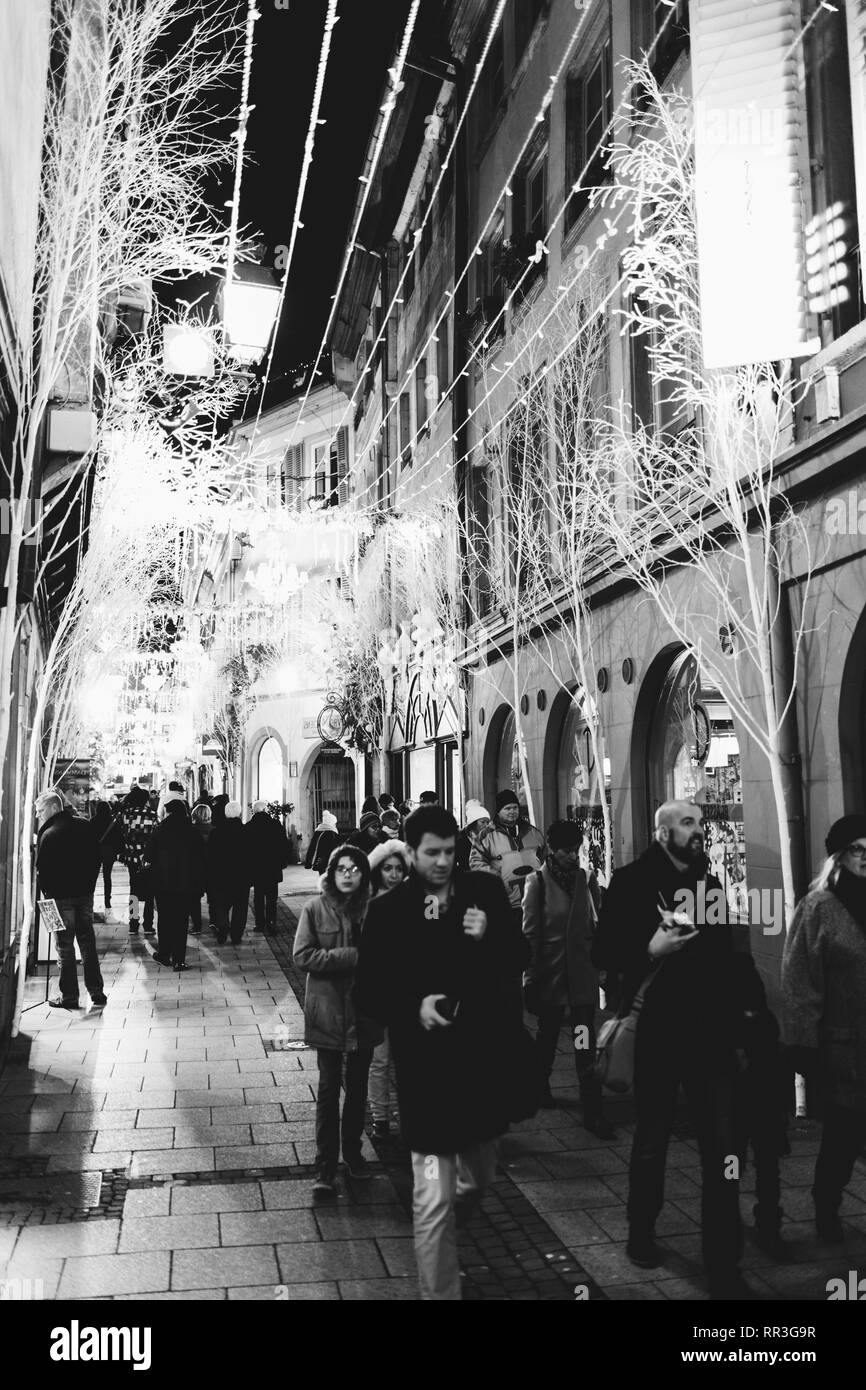 Strasburgo, Francia - Nov 29, 2017: pedoni camminare in tarda serata sotto le ghirlande illuminato e il Mercato di Natale decorazioni su l'iconica Rue des Orfevres a Strasburgo - bianco e nero Foto Stock