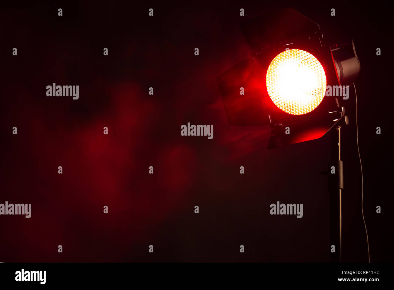 Luce rossa con fumo nel buio. Attrezzature per foto in studio. Foto Stock