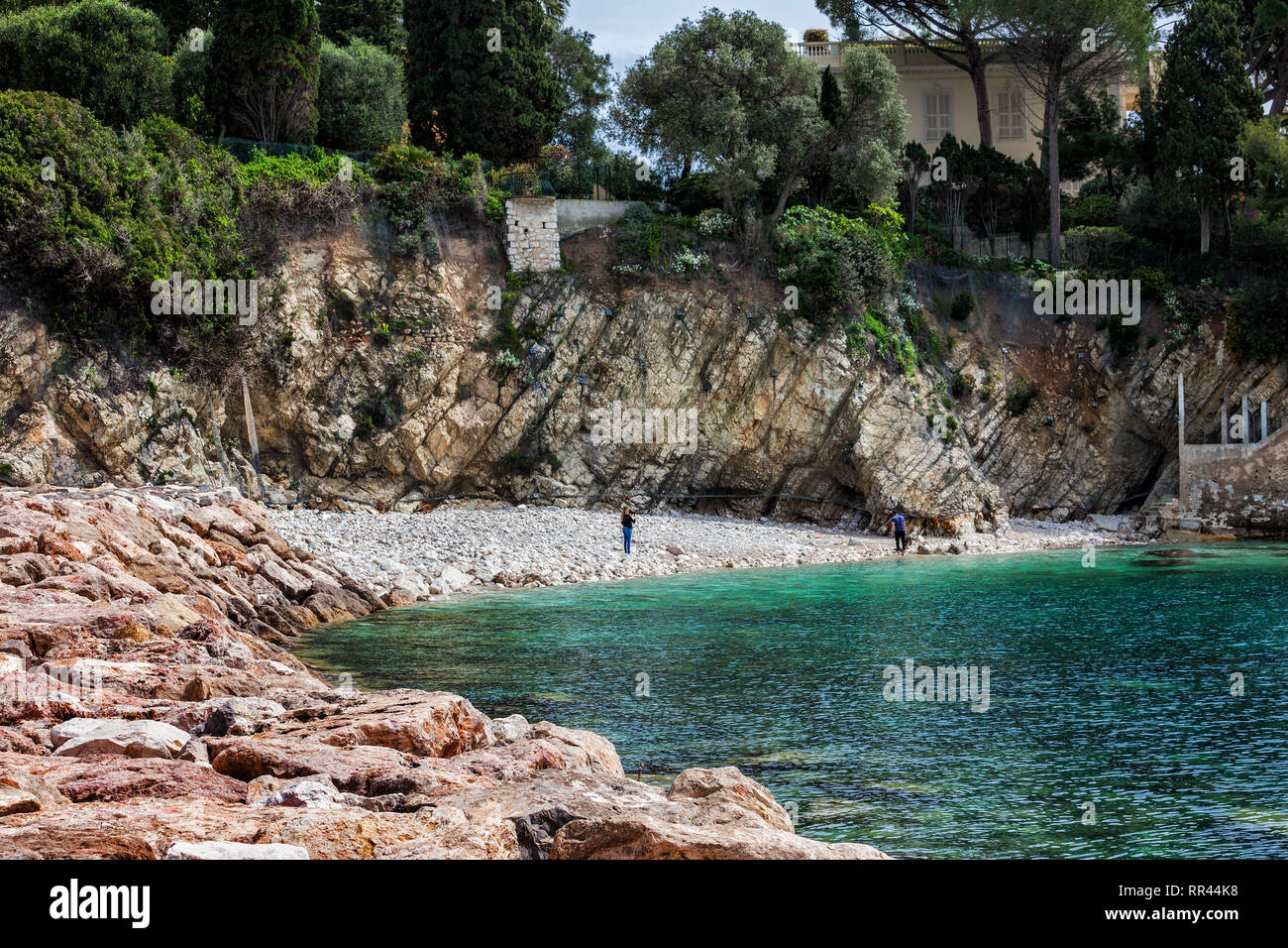 Piccola spiaggia rocciosa al di sotto di scogliera e mare nella baia di Villefranche sur Mer sulla Riviera Francese in Francia Foto Stock