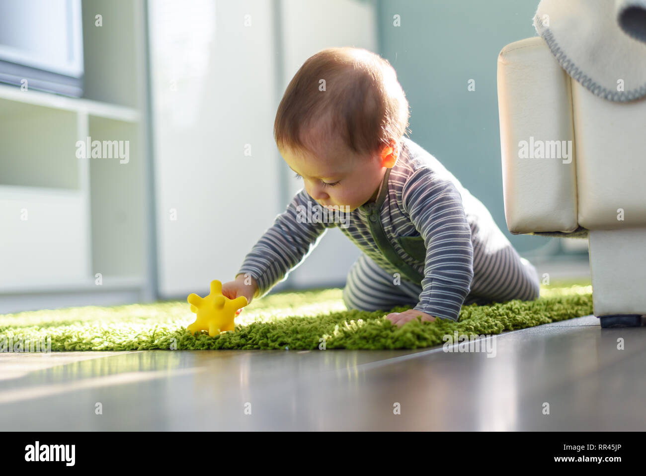 Riproduzione di ragazzo sul tappeto verde closeup. Concetto di infanzia Foto Stock