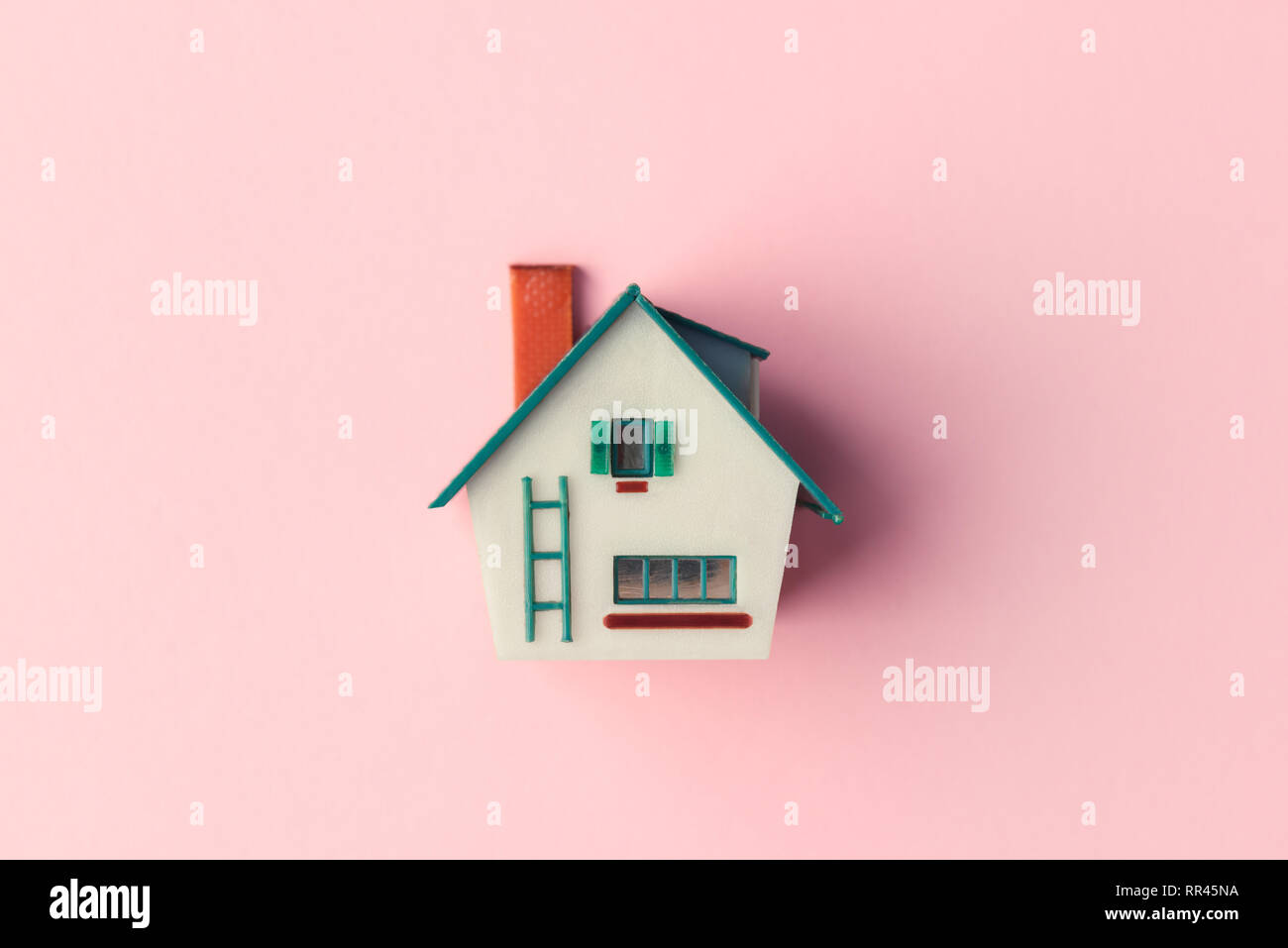 Casa in plastica modello su sfondo rosa. Immobiliare di concetto Foto Stock