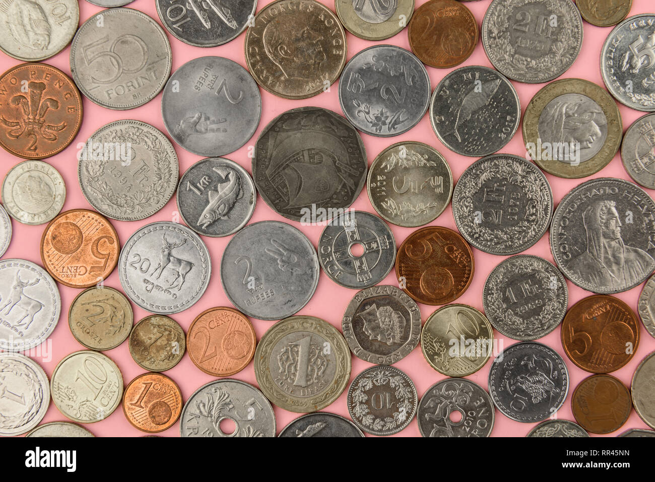 Paese diverse monete su sfondo rosa Foto Stock