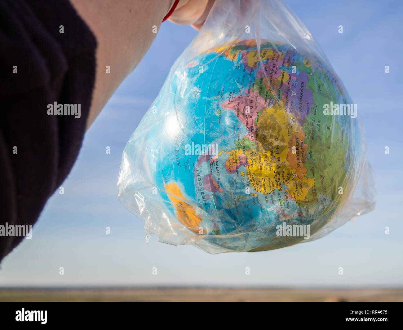 Una persona con un globo terrestre o il pianeta terra nelle sue mani in un sacchetto di plastica. Concetto di ecologia Foto Stock
