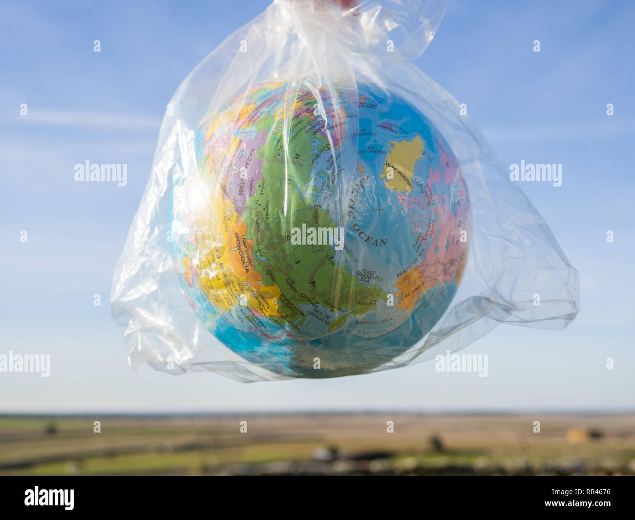 Una persona con un globo terrestre o il pianeta terra nelle sue mani in un sacchetto di plastica. Concetto di ecologia Foto Stock