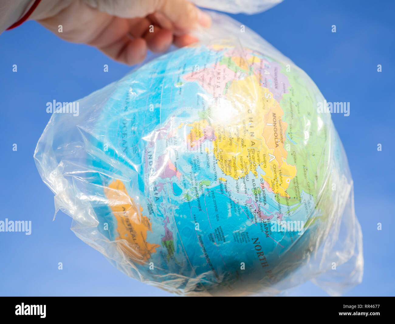 Una persona con un globo terrestre o il pianeta terra nelle sue mani in un sacchetto di plastica. Concetto di ecologia Foto Stock