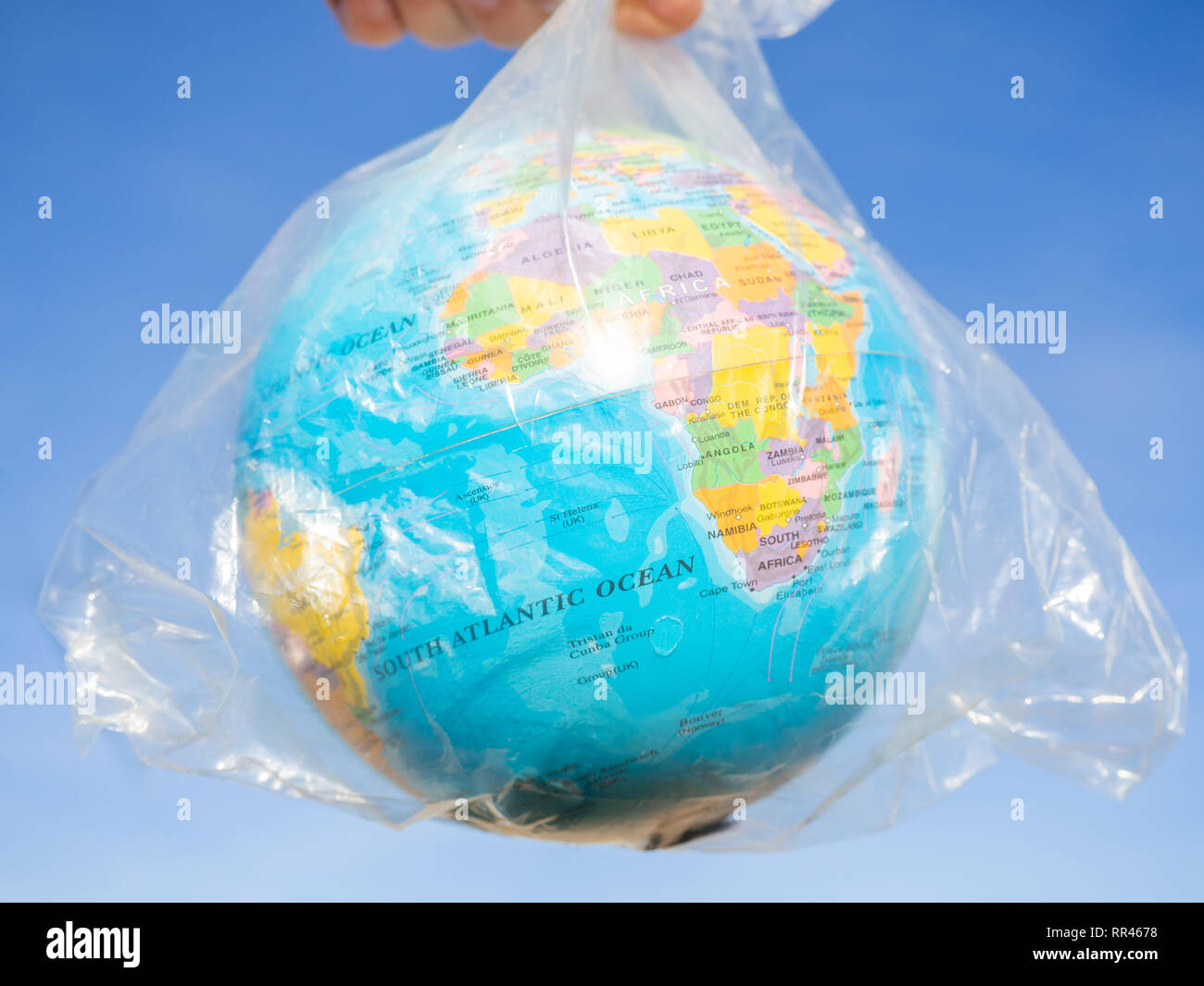 Una persona con un globo terrestre o il pianeta terra nelle sue mani in un sacchetto di plastica. Concetto di ecologia Foto Stock