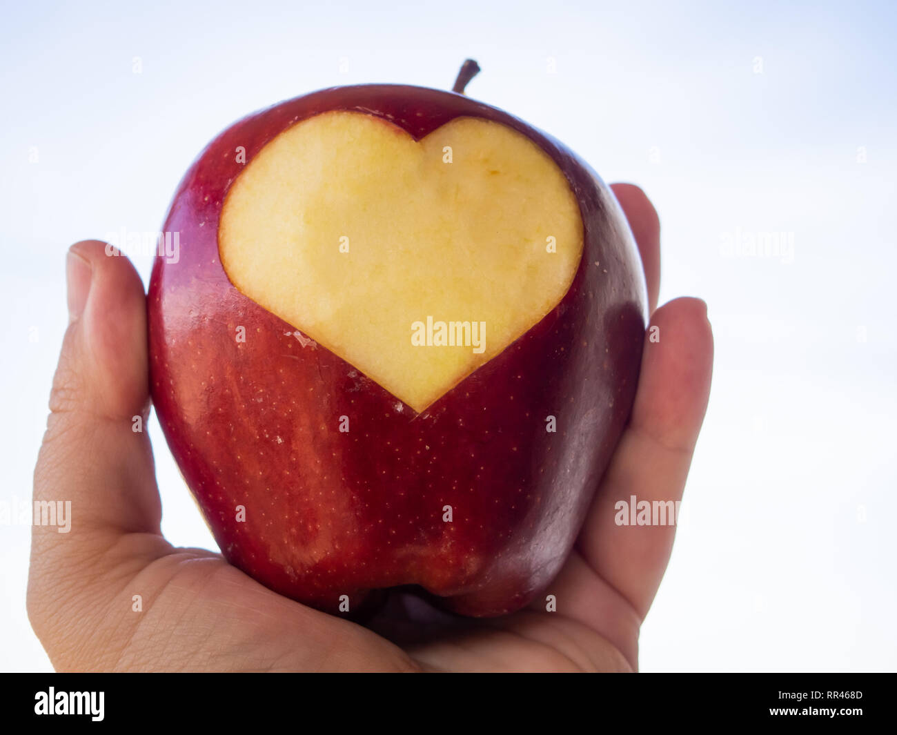 Una persona con un rosso apple nelle sue mani con un taglio a forma di cuore. Concetto di salute Foto Stock