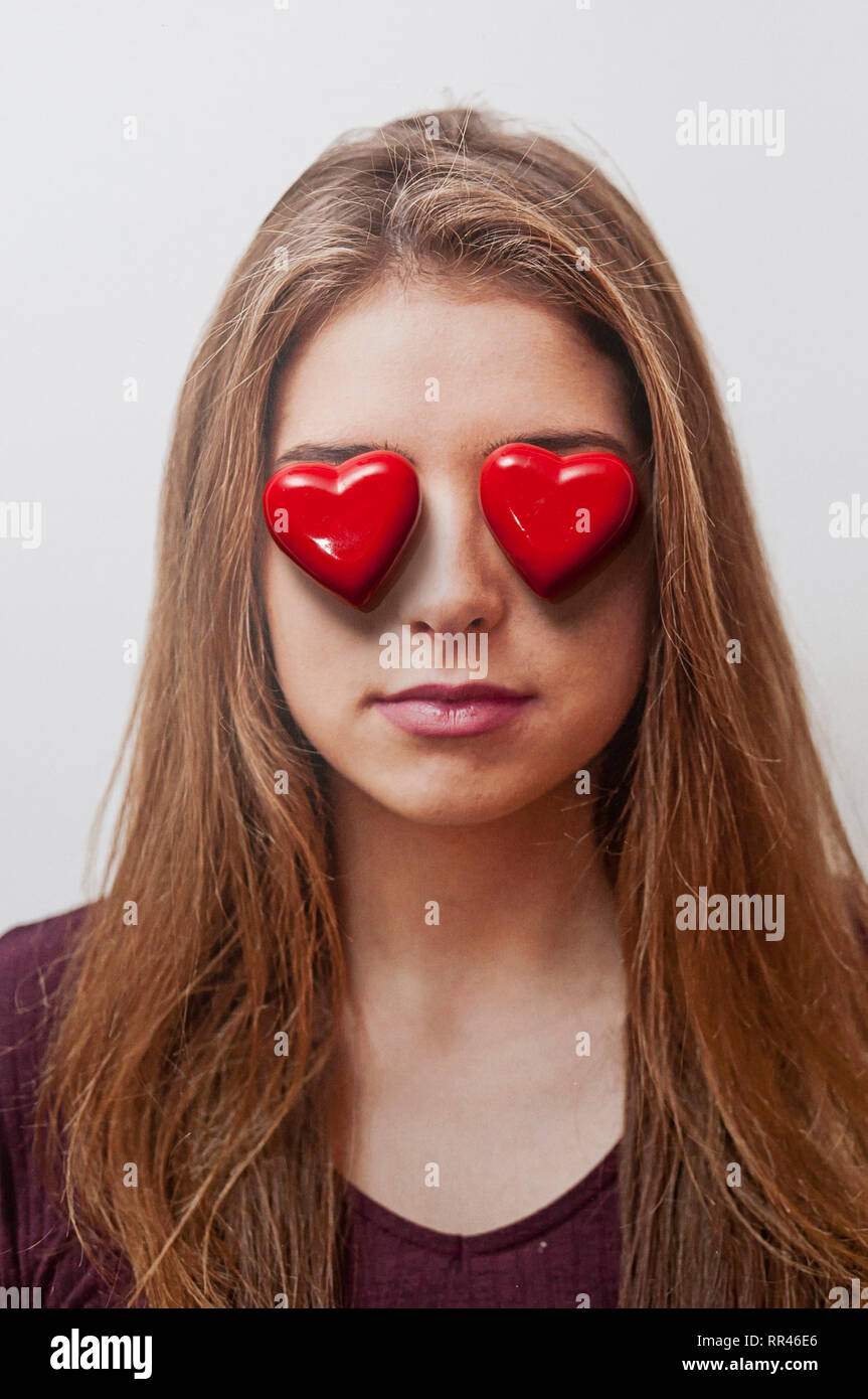 Bruna ragazza con due forme di cuore oltre i suoi occhi, adolescente nel concetto di amore Foto Stock
