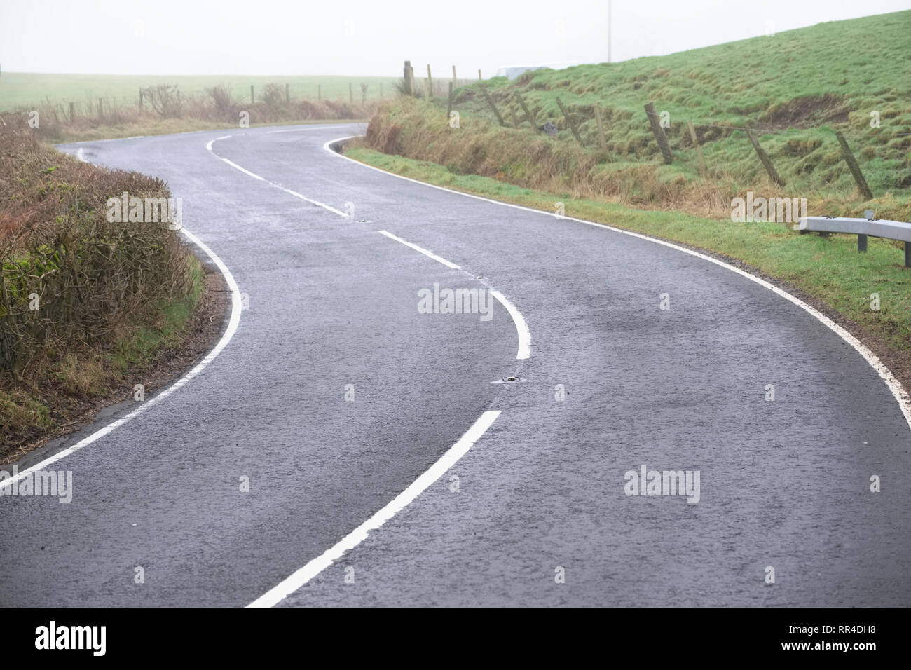 Paese curva vuota strada rurale linee bianche e hedge Foto Stock