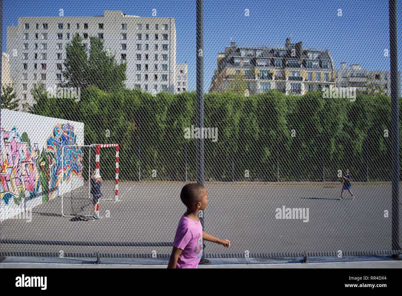 I bambini giocano in campo da calcio recintato, Jardins d'Eole, Rue du Département, 75018, Parigi, Francia Foto Stock