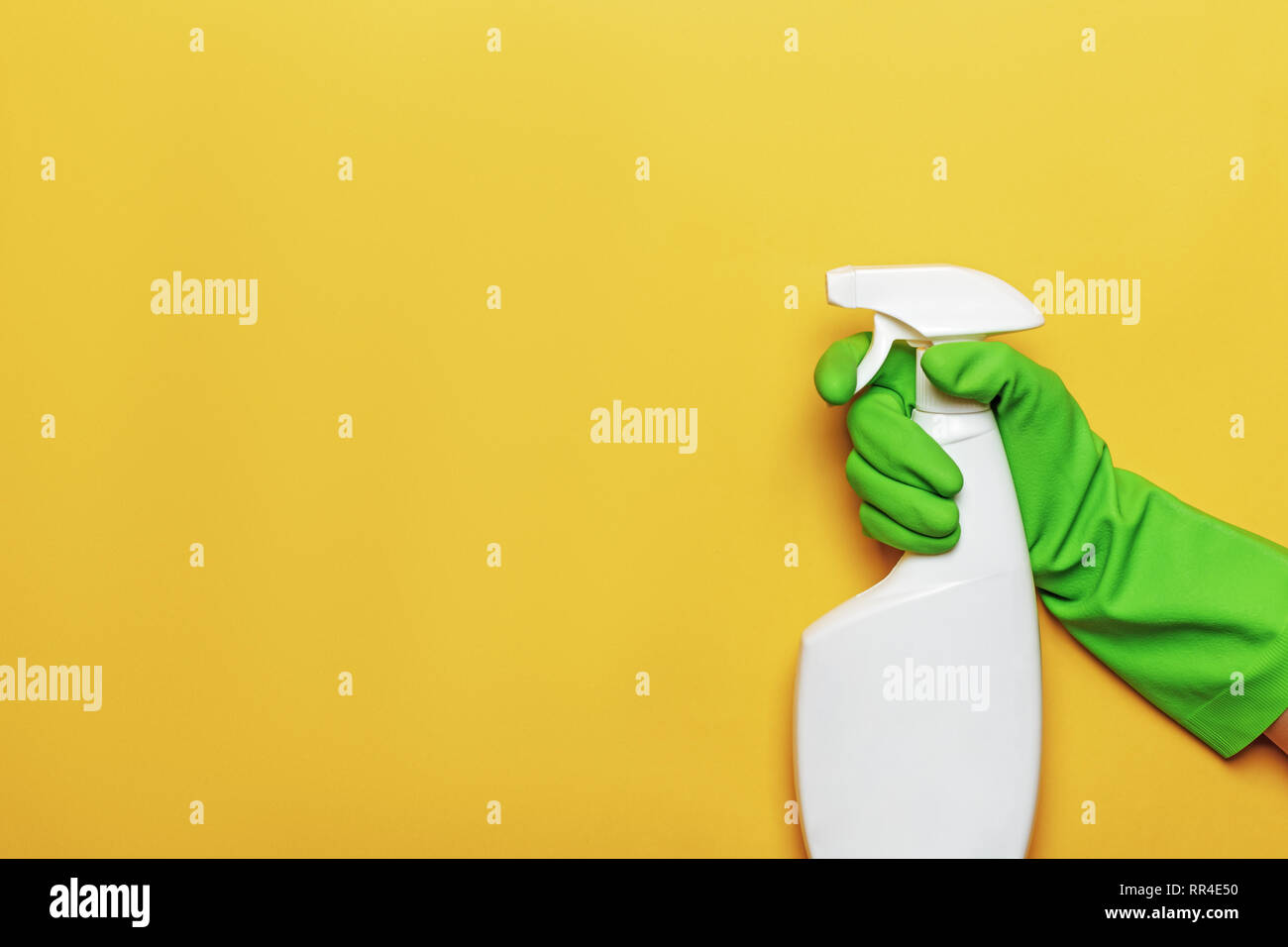 Un lavoratore in mano una gomma di guanto protettivo con un flacone spray su un giallo sfondo colorato. Il concetto di pulizia, prendersi cura della casa. Foto Stock