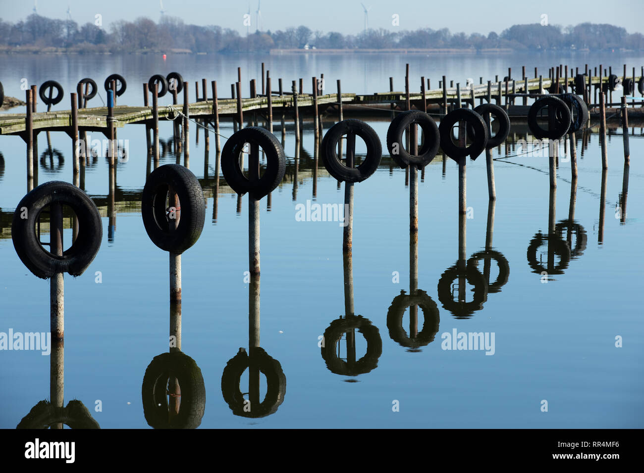 24 febbraio 2019, Bassa Sassonia, Dümmerlohausen: un pontile e paracarri coperto con pneumatici può essere visto nel Dümmer vedere con sole splendente e temperature intorno ai 15 gradi Celsius prima molla. Foto: Friso Gentsch/dpa Foto Stock