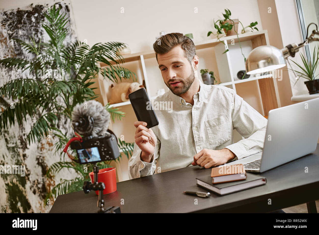 Nuovo gadget. La tecnologia blogger che mostra il nuovo smartphone con fotocamera sul primo piano. Social Media. Blog. Contenuto Foto Stock