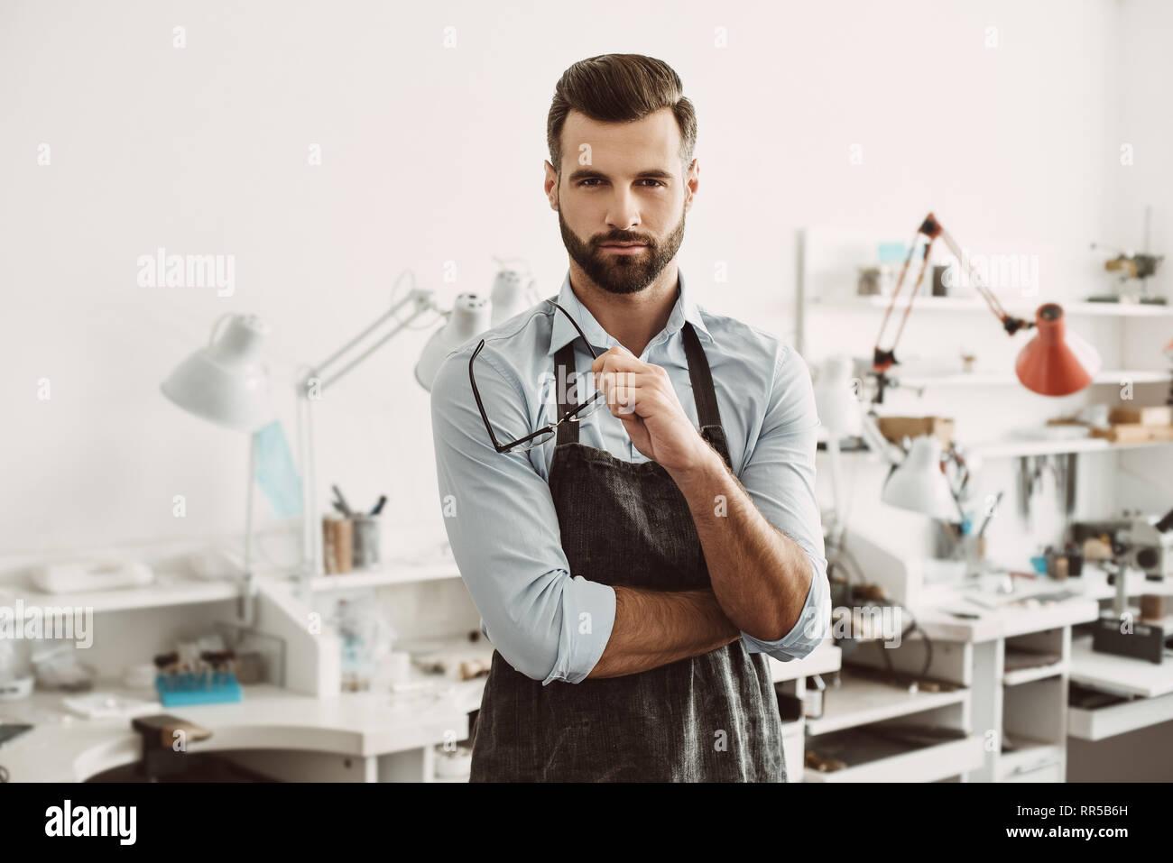 Certi leader. Ritratto di fiducioso gioielliere maschio indossando grembiuli e occhiali di trattenimento permanente, mentre in gioielleria studio. Foto Stock