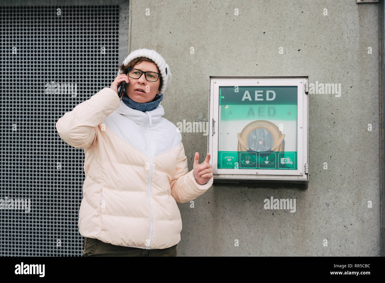 Medicina rianimazione cardiopolmonare chiamata di emergenza. La donna caucasica utilizza telefono chiamando 911 aiuto. il riquadro del dispositivo aed defibrillatore automatico malattia Foto Stock
