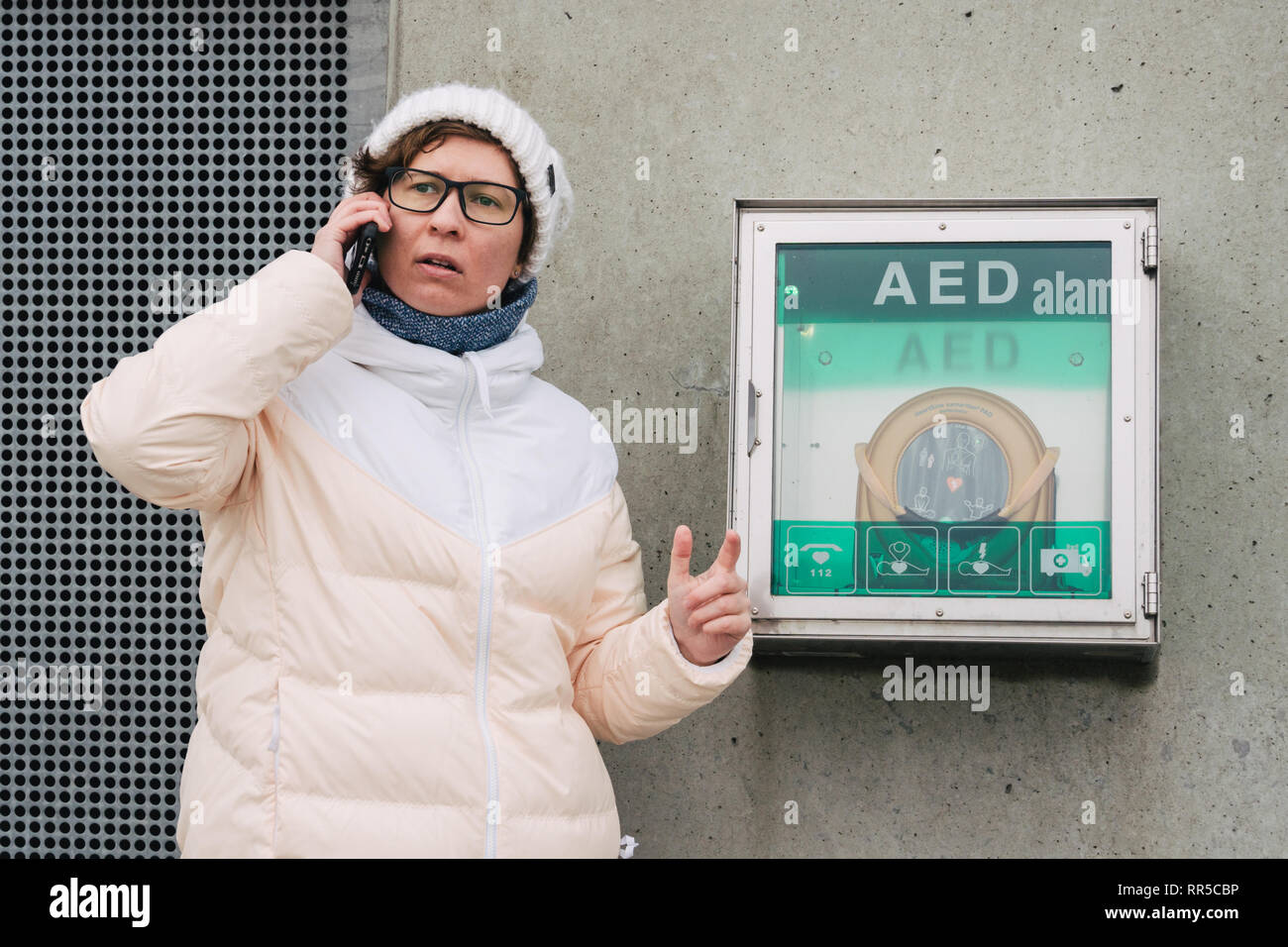 Medicina rianimazione cardiopolmonare chiamata di emergenza. La donna caucasica utilizza telefono chiamando 911 aiuto. il riquadro del dispositivo aed defibrillatore automatico malattia Foto Stock