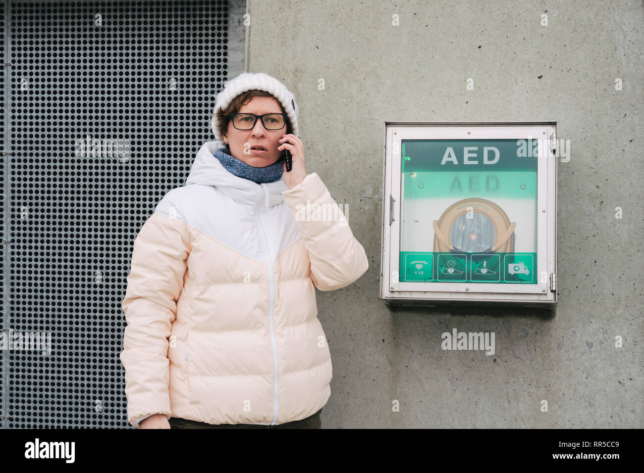 Medicina rianimazione cardiopolmonare chiamata di emergenza. La donna caucasica utilizza telefono chiamando 911 aiuto. il riquadro del dispositivo aed defibrillatore automatico malattia Foto Stock