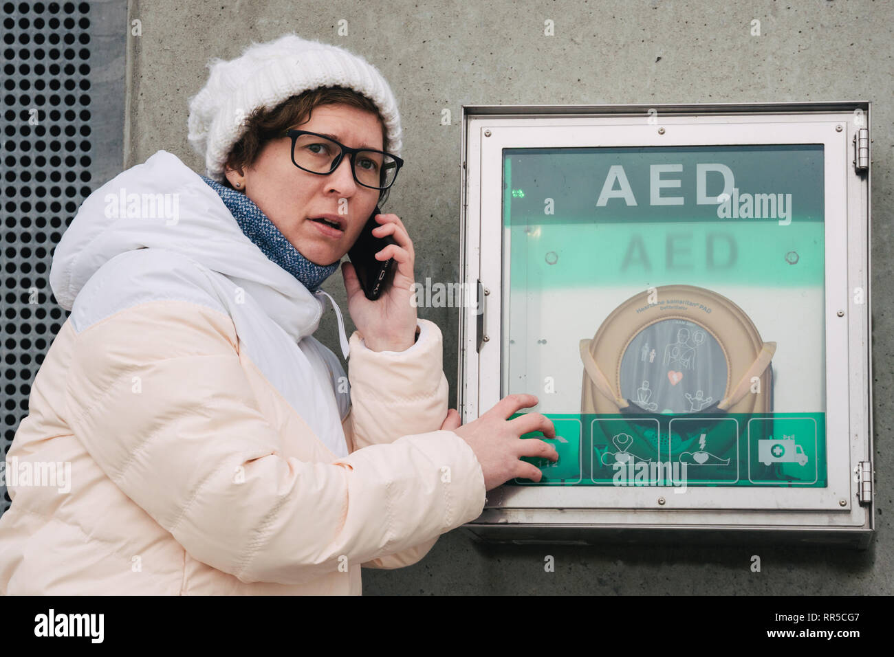 Medicina rianimazione cardiopolmonare chiamata di emergenza. La donna caucasica utilizza telefono chiamando 911 aiuto. il riquadro del dispositivo aed defibrillatore automatico malattia Foto Stock
