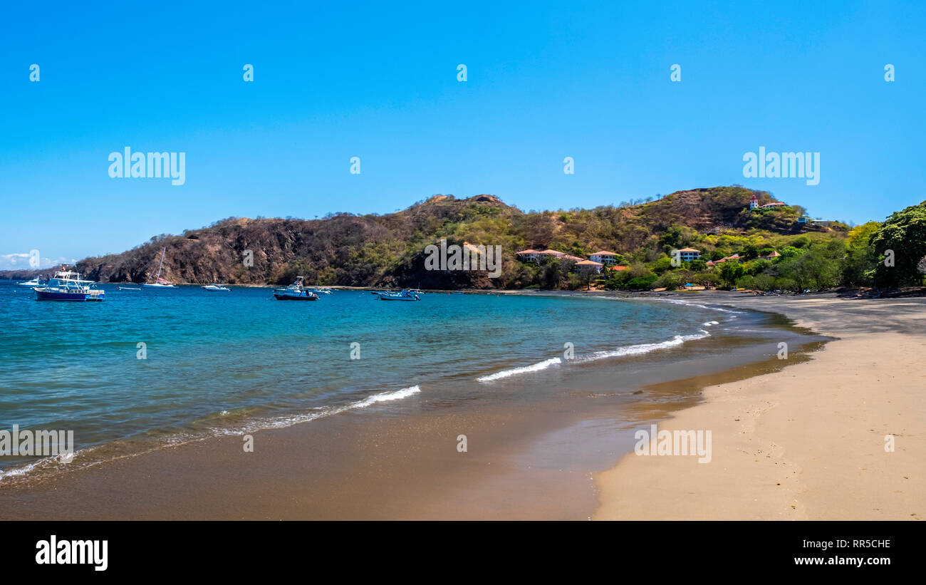 La spiaggia di sabbia bianca di Playa Ocotal e, Costa Rica, contrasta con il blu del cielo e le acque blu dell'Oceano Pacifico. Foto Stock