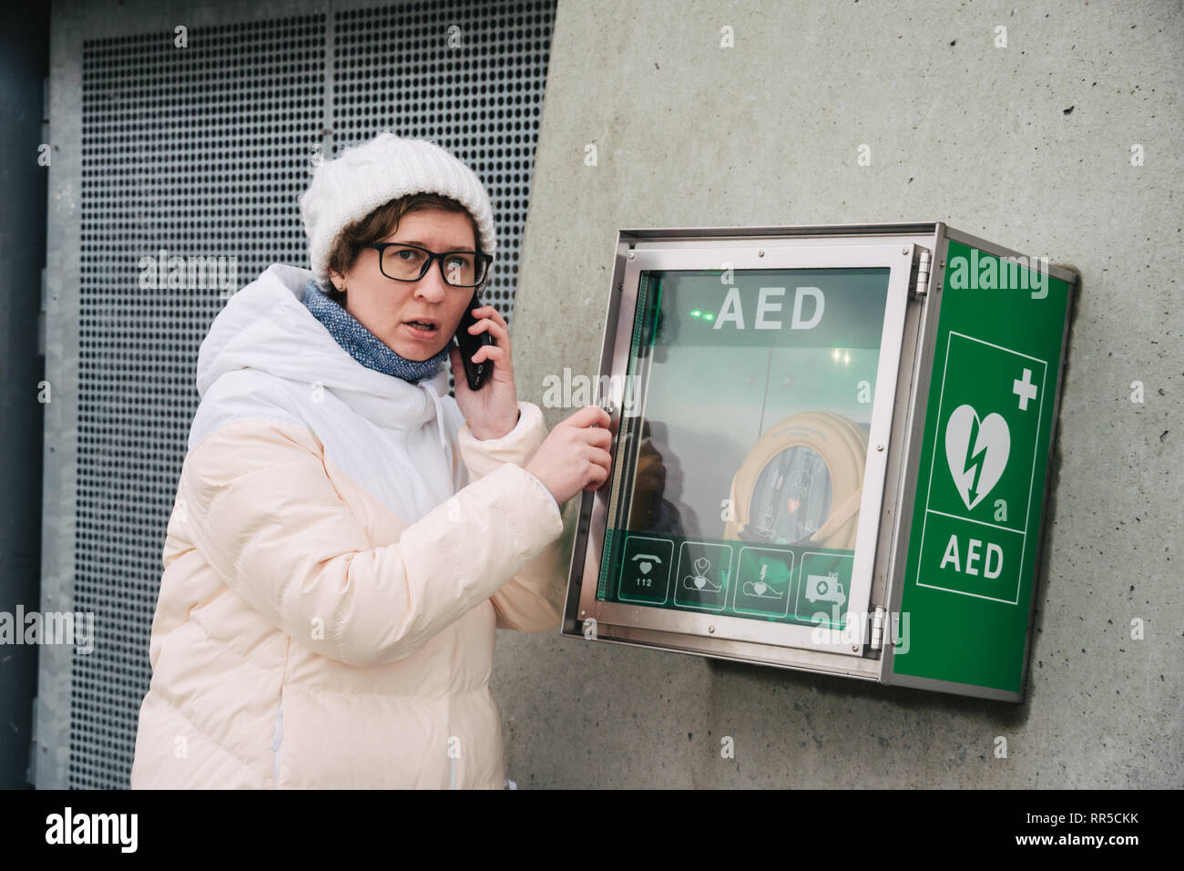 Medicina rianimazione cardiopolmonare chiamata di emergenza. La donna caucasica utilizza telefono chiamando 911 aiuto. il riquadro del dispositivo aed defibrillatore automatico malattia Foto Stock