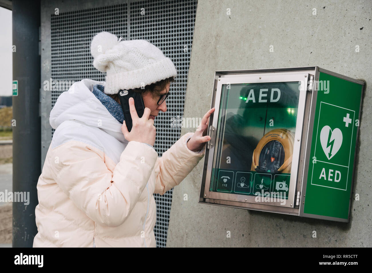 Medicina rianimazione cardiopolmonare chiamata di emergenza. La donna caucasica utilizza telefono chiamando 911 aiuto. il riquadro del dispositivo aed defibrillatore automatico malattia Foto Stock