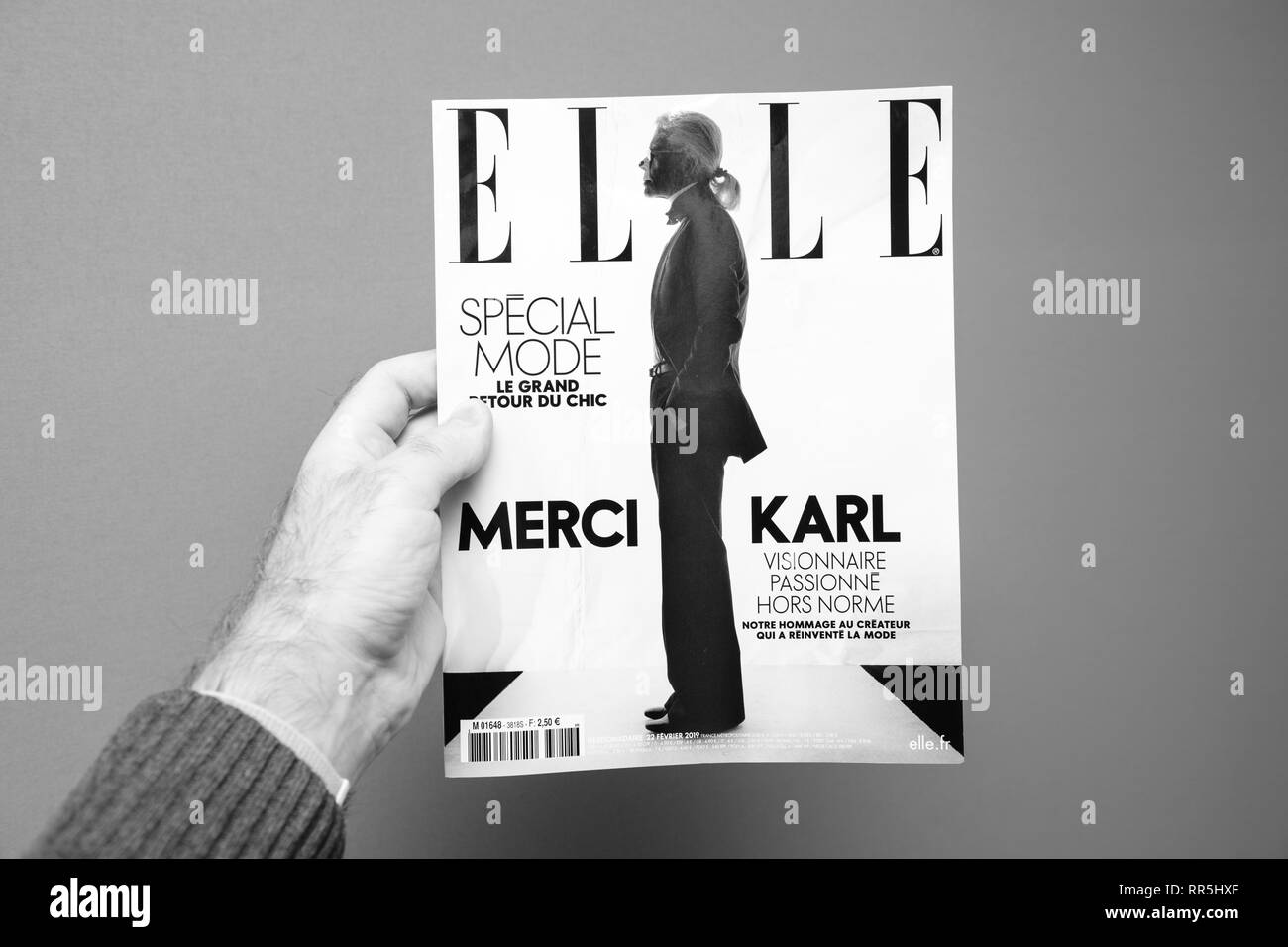 Parigi, Francia - Feb 23, 2019: l'uomo che mostra il francese ELLE magazine tributo a copertura di Karl Lagerfeld morte, iconico designer di moda sono morti di età compresa tra i 85 - bianco e nero Foto Stock