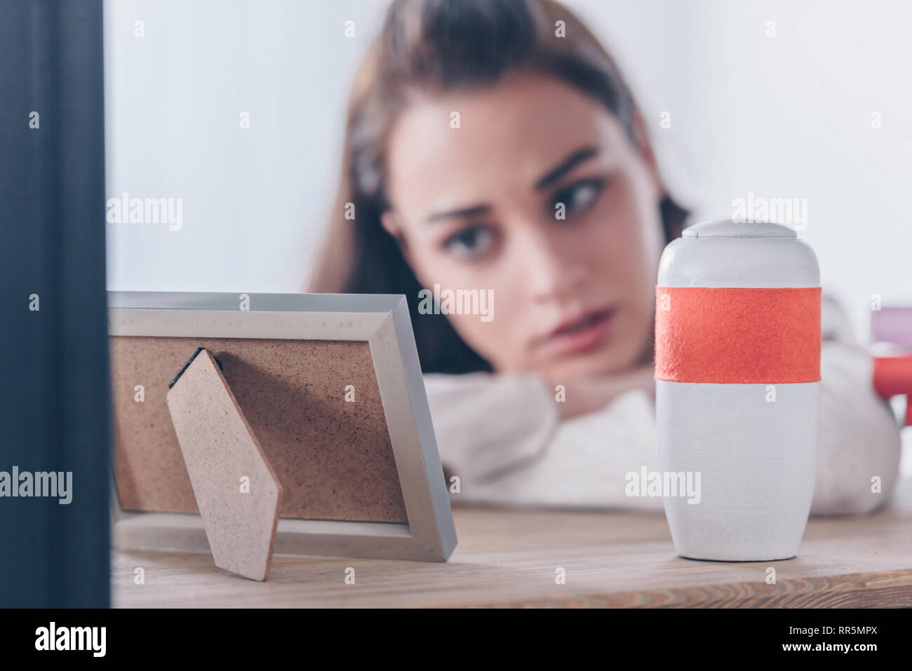 Messa a fuoco selettiva di Cornice foto e urna funeraria con donna ricalcato su sfondo Foto Stock