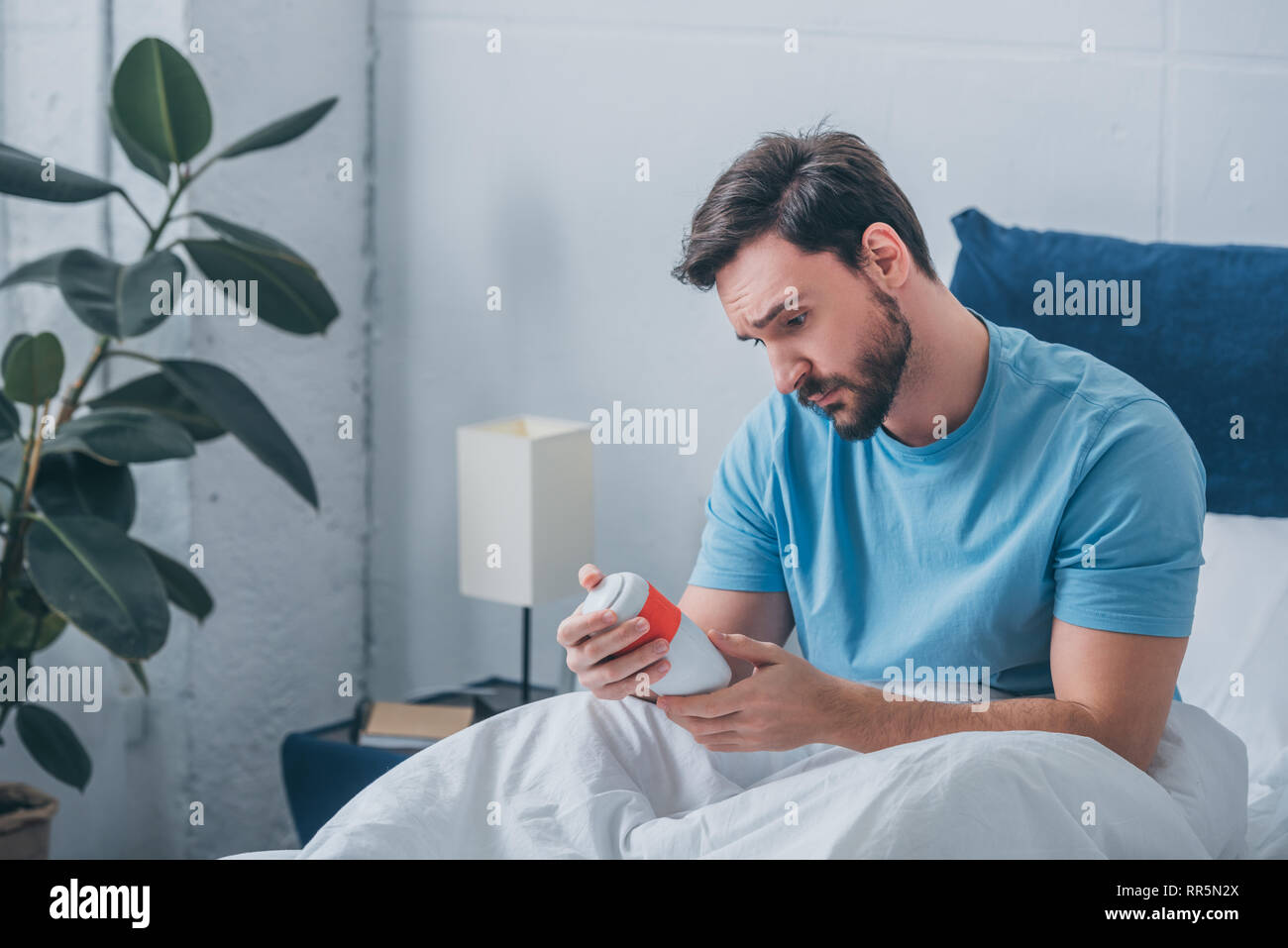 Premuto un uomo guarda urna funeraria a letto Foto Stock