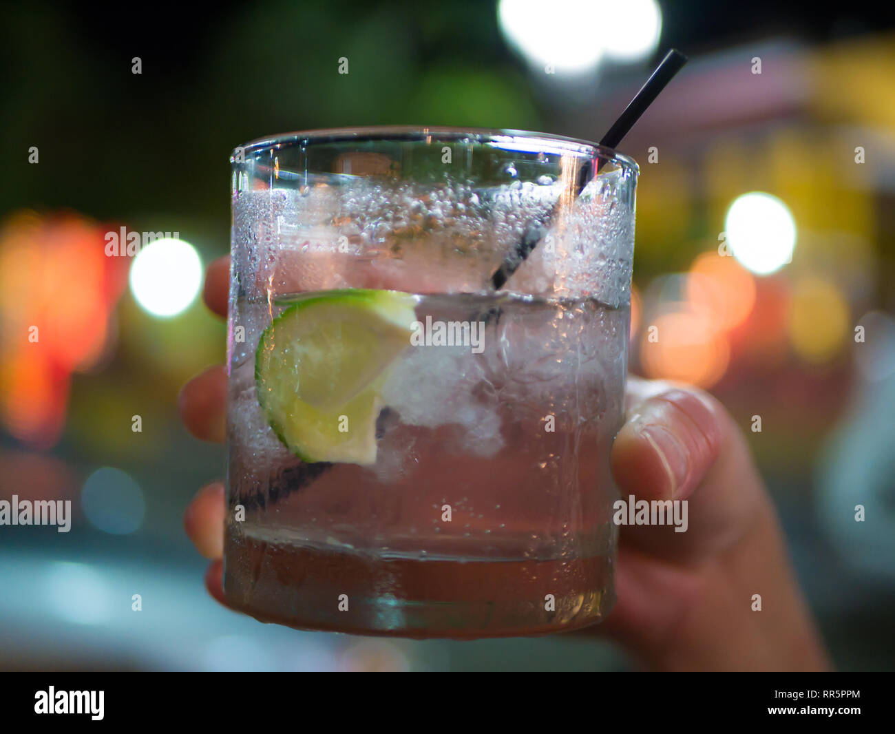 Bere un bicchiere in mano la donna a parte o di celebrazione del nuovo anno la notte, sfondo sfocato. Foto Stock