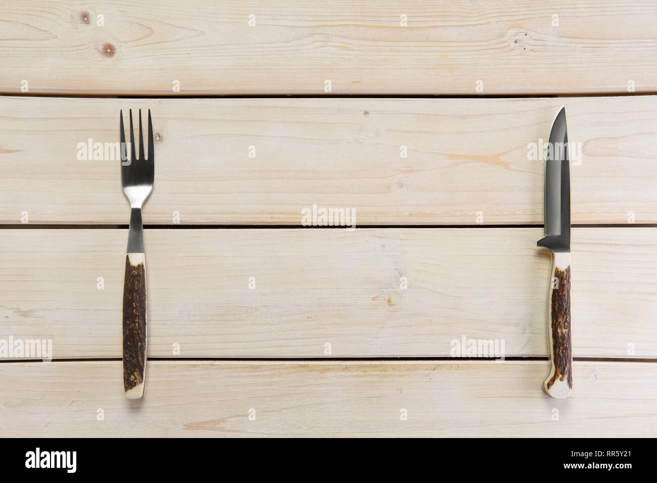 Vista aerea del turista coltello e forchetta con manico in corno di vuoto sul tavolo di legno Foto Stock