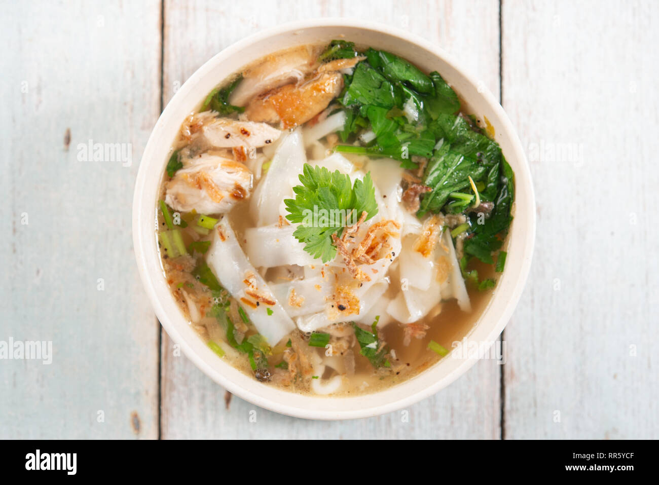 Asian kway teow zuppa noodles e pollo in vaso su sfondo di legno. Vista superiore piatta. laici Foto Stock