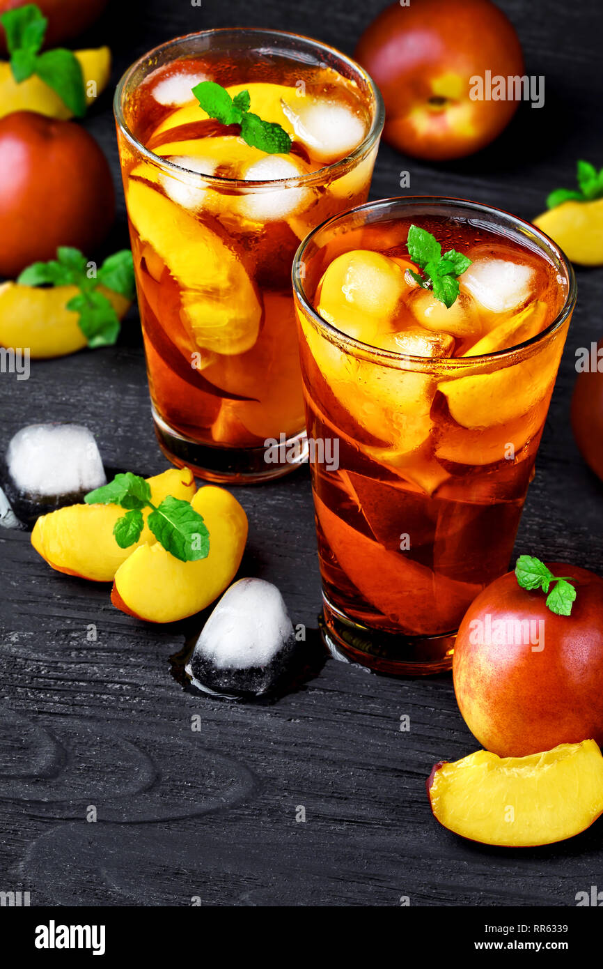 Peach ice tea in un bicchiere con la menta su tavoli in legno nero(fuoco selettivo). Foto Stock
