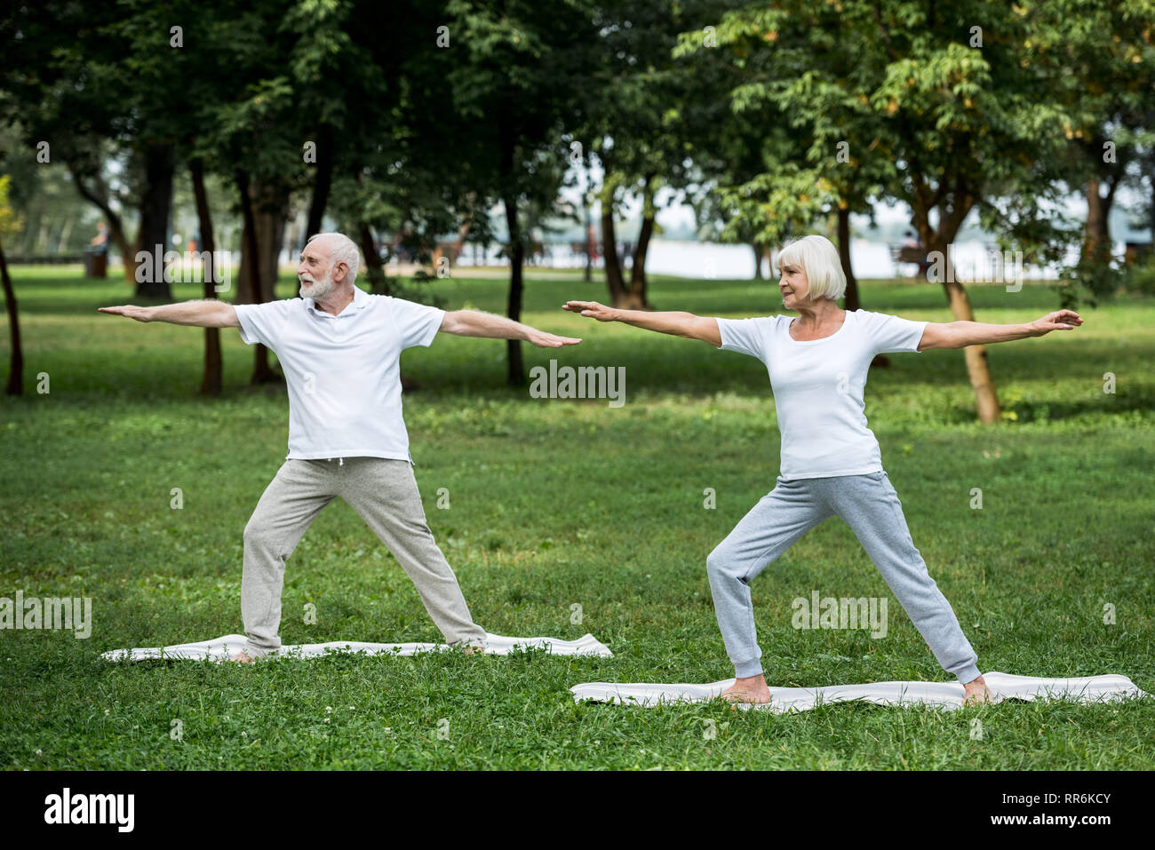 Coppia senior pratica Guerriero II pone in piedi su Materassini da yoga Foto Stock