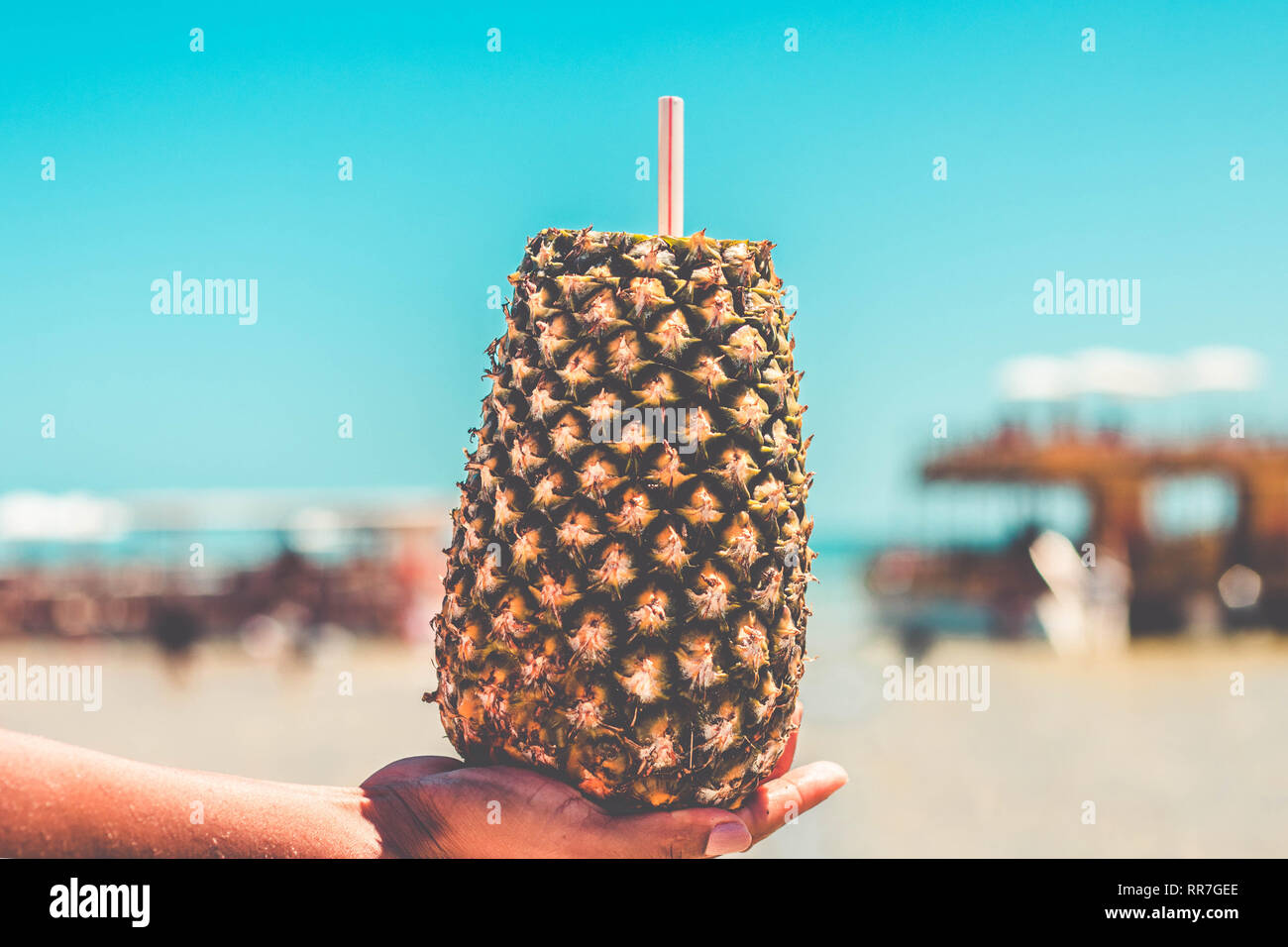 Mano azienda ananas cocktail su un oceano e cielo blu sullo sfondo Foto Stock