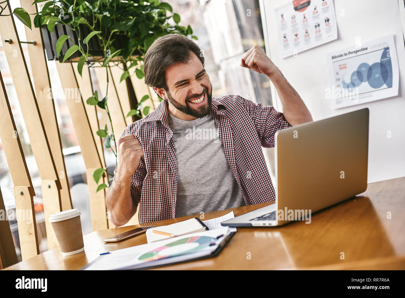 Professional economista maschio cerca le informazioni necessarie sul computer portatile, felice di ricevere ad alto profitto netto, spende importante operazione bancaria. Bel maschio trader analizza il mercato finanziario, facendo sì-gesto. Concetto di successo Foto Stock