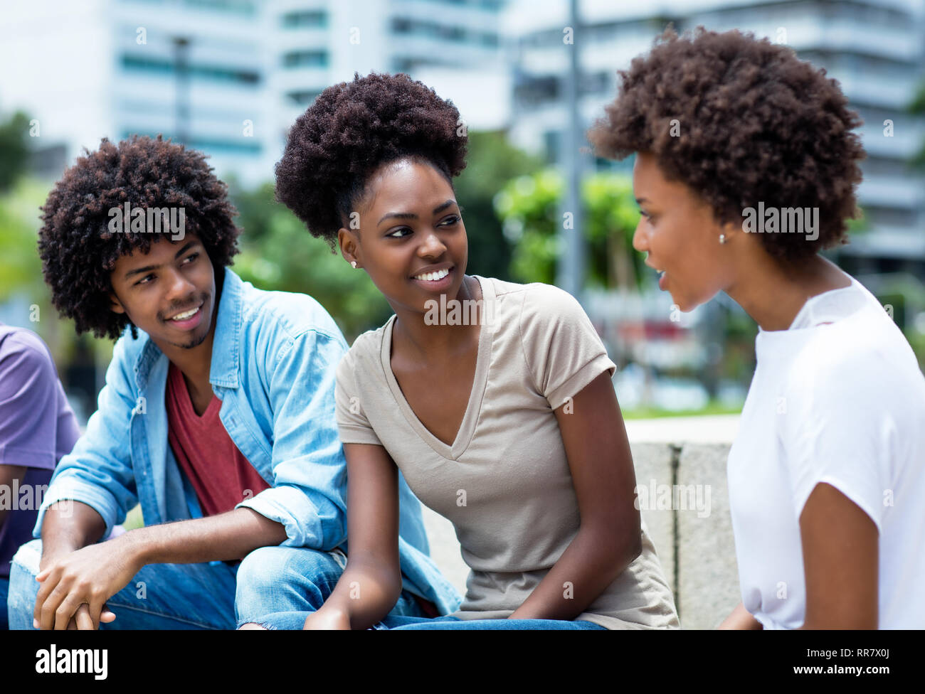 Gruppo di parlare americano africano i giovani adulti all'aperto in estate Foto Stock