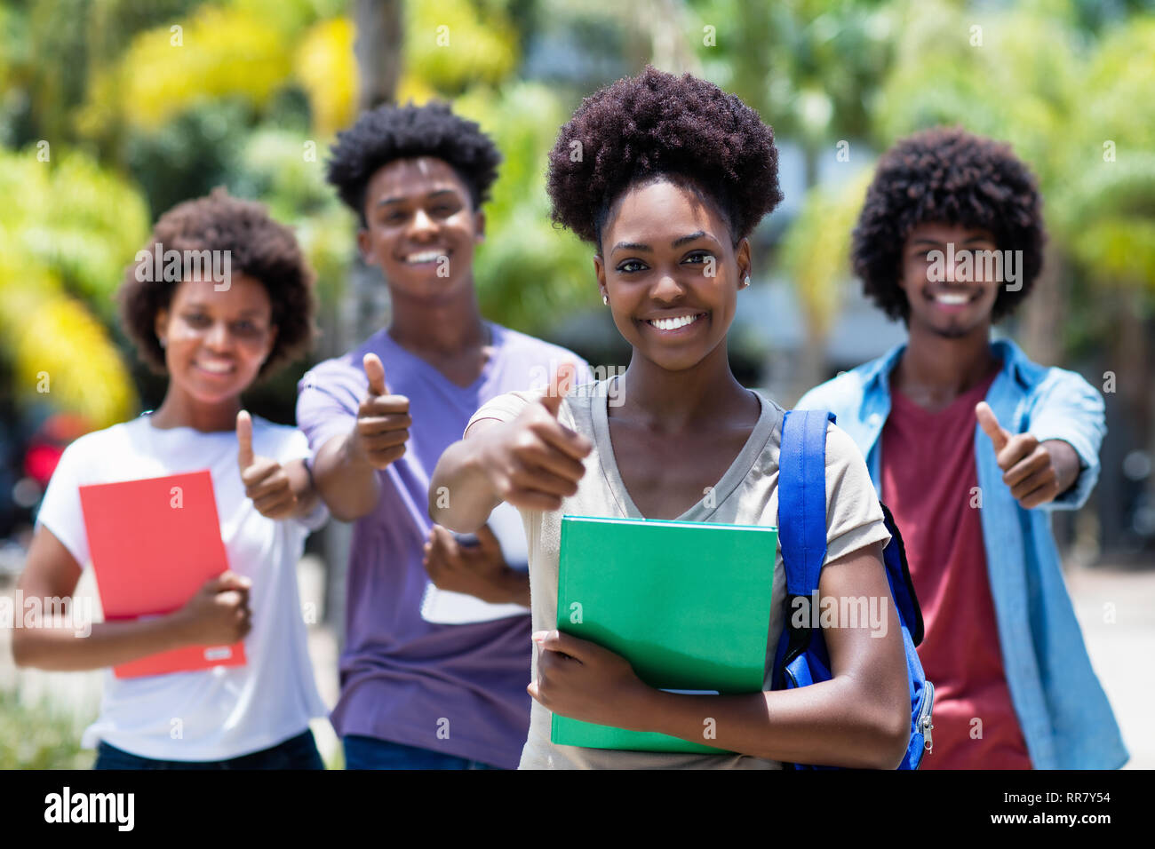 Successo femmina africana studente con gruppo di African American studenti all'aperto in estate Foto Stock