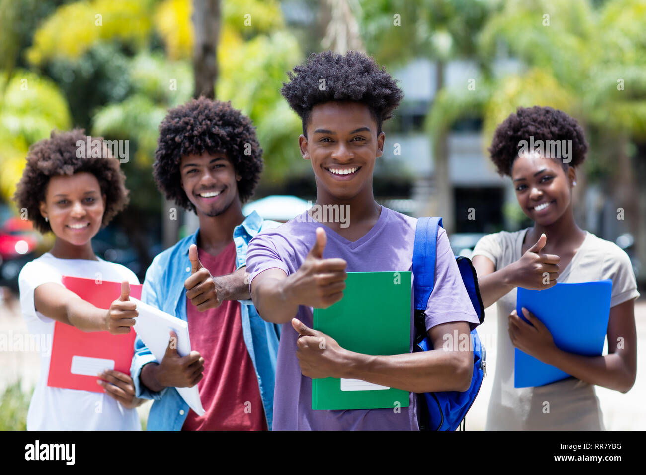Successo maschio africano studente con gruppo di African American studenti all'aperto in estate Foto Stock