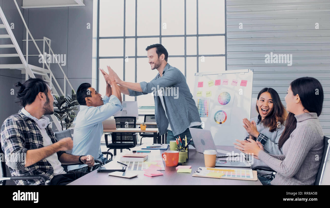 Il direttore creativo team di piombo clap mano con il team di designer al tavolo riunioni.La discussione idea creativa in ufficio Foto Stock
