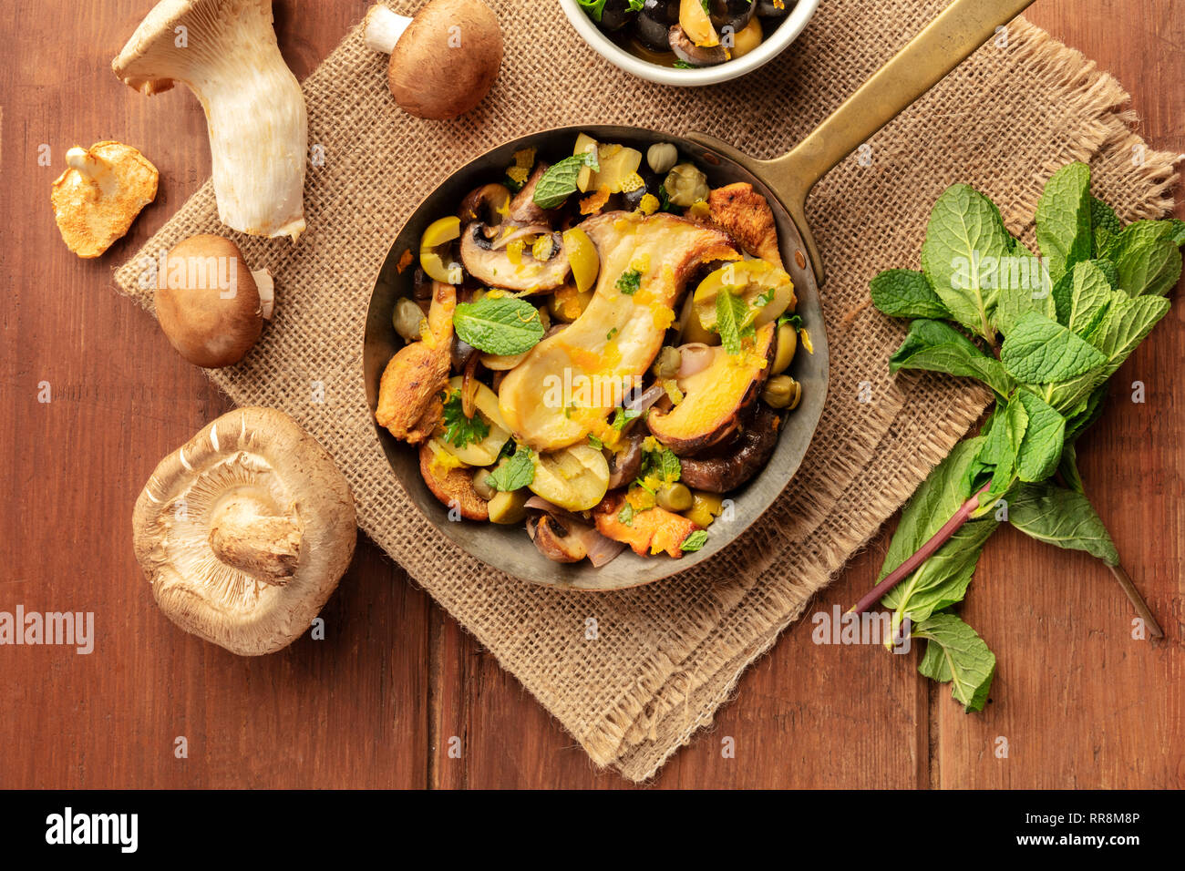 Una foto aerea di un rustico di funghi e olive rosolare in una ghisa padella con menta e porcini Foto Stock