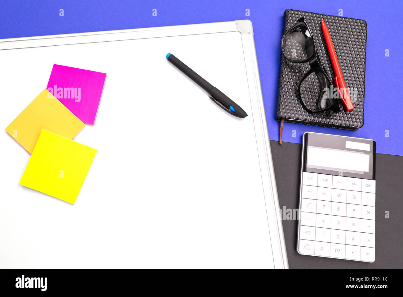 Ambiente di lavoro moderno con office-board, penna e calcolatrice isolato blu su sfondo nero Foto Stock