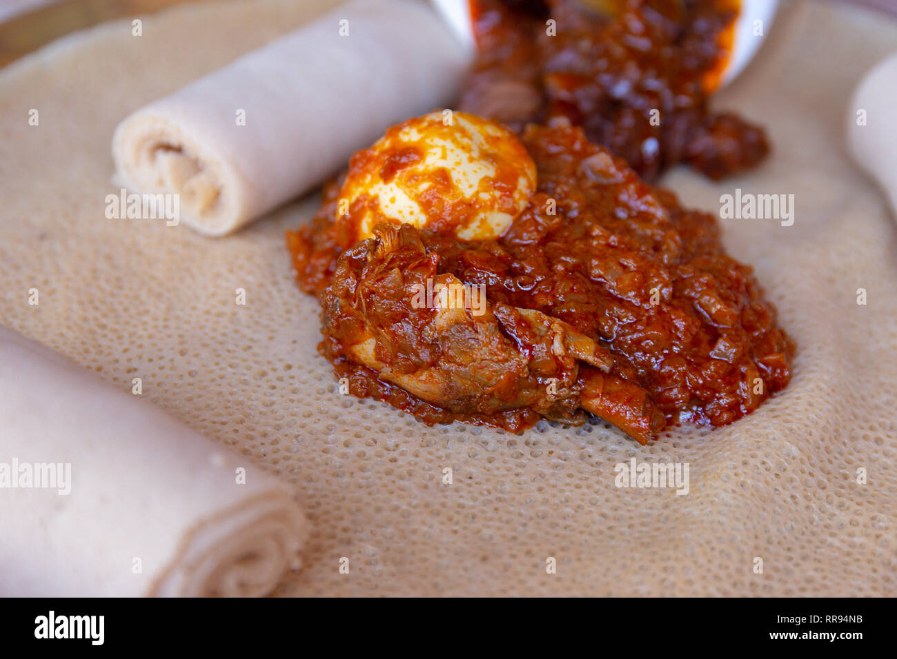 Ristoranti africani. Pollo e uovo Doro Wat con Injera - una pasta madre flatbread realizzato da teff farina. È il cibo nazionale dell'Etiopia, Eritrea, Somalia Foto Stock